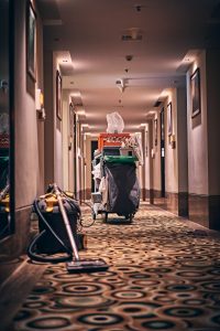 vacuum and cleaning items on carpet in hotel hallway