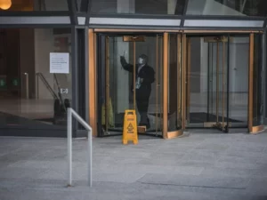 janitor cleaning revolving door of commercial facility